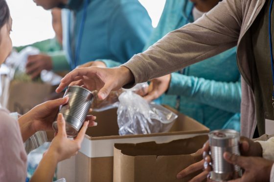 Food bank volunteer accepts a canned food item during a food drive.