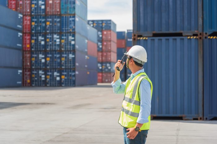 Foreman control loading Containers box from Cargo freight ship in Warehouse shipping transportation